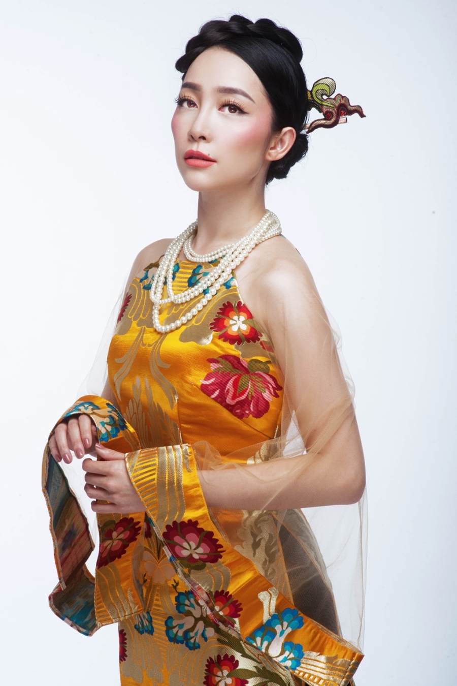 Cùng một phom dáng nhưng thiết kế trong ảnh được thay đổi chất liệu, màu sắc, hoa văn. Tông vàng vương giả giúp người mặc trẻ trung, nữ tính hơn.