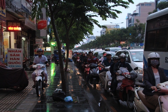  Trong khi đó, người đi xe máy cũng phải xếp hàng dài hoặc leo lên lề đường để lưu thông 