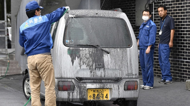  Người dân địa phương rửa các phương tiện bị tro bụi phủ đen (Ảnh: Reuters) 