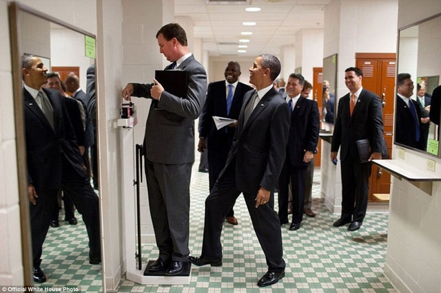 Tổng thống Obama đặt chân lên chiếc cân để trêu đùa một nhân viên khi người này đang kiểm tra cân nặng của mình.