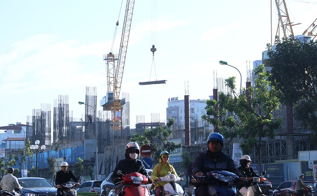 Các dự án xây dựng chung cư, nhà thương mại cao tầng liên tục mọc lên hai bên tuyến đường Lê Văn Lương - Tố Hữu - Lê Trọng Tấn. Cần cẩu sắt lơ lửng trên đầu người tham gia giao thông.