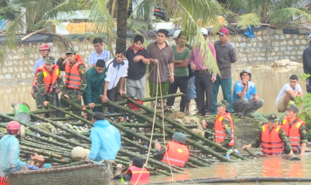 Các chiến sĩ bộ đội, công an ngâm mình trong lòng nước lũ đưa bè cá để khơi thông dòng chảy qua cầu Thiện Chánh