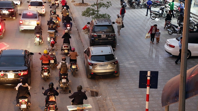 Chiếc ô tô màu xám đỗ trên phố Giảng Võ, một hàng bánh xe trên vỉa hè, một hàng bánh xe dưới đường. Đây là cách đô xe “lách luật mà các tài xế hay áp dụng.