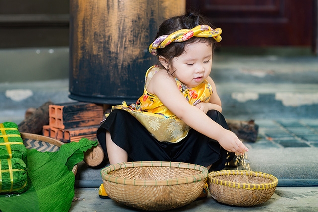 Bé Mimi mặc bộ trang phục bằng gấm cách tân từ trang phục của phụ nữ Việt ngày xưa. Trên đầu cô bé còn đội một chiếc mấn xinh xắn. Đây là kiểu trang phục đang thịnh hành mùa Tết năm nay.
