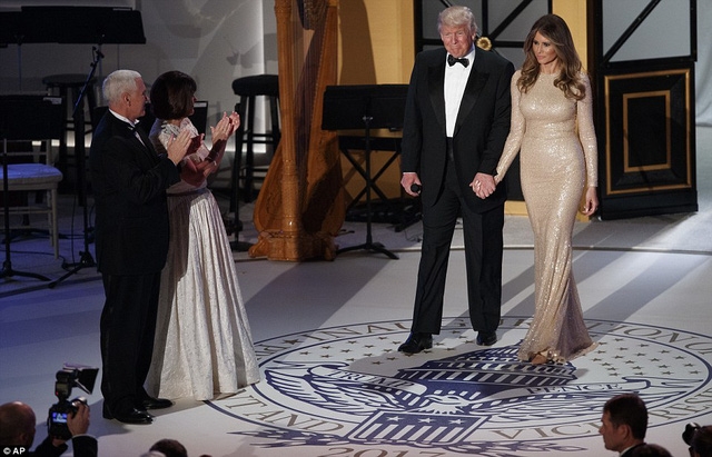  Phu nhân của ông Trump, bà Melania, với tông màu trang điểm nhẹ, xuất hiện trong bữa tiệc với một chiếc đầm đuôi cá óng ánh của nhà thiết kế nổi tiếng Reem Arca thay vì chiếc đầm của nhà thiết kế Ralph Lauren như đồn đoán trước đó. Bà sánh vai bên chồng bước ra sân khấu giữa những tràng pháo tay của hơn 1.000 khách mời. (Ảnh: AP) 