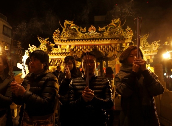 People pray with incense sticks at a temple as they celebrate the Lunar New Year in China Town, in Yokohama