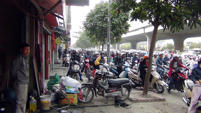 Một cửa hàng sửa chữa xe máy đem xe chắn ngang vỉa hè để ngăn dòng người điều khiển xe máy đi qua trước cửa nhà