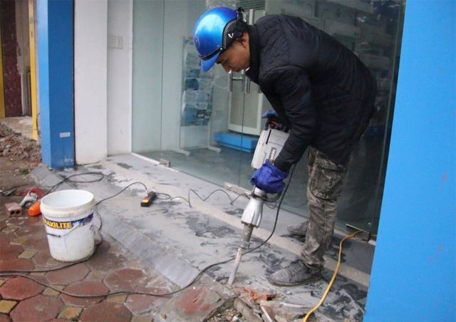 Lực lượng chức năng sáng nay tiếp tục dùng máy khoan bê tông để phá các bục bê tông lấn chiếm vỉa hè, lòng đường tại tuyến phố Tôn Đức Thắng (Đống Đa, Hà Nội).