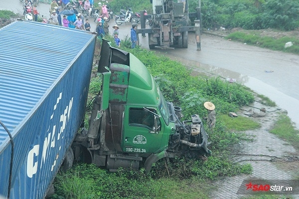 Cách đó không xa, chiếc container chạy ngược chiều do mải dùng điện thoại quay lại cảnh tai nạn nên lao xuống phần đường cách mặt cầu khoảng 3m.